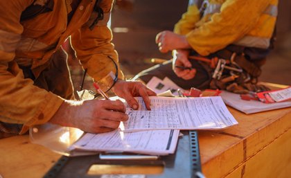 Close up of mine worker in high vis writing on a piece of paper